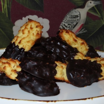 Bolachas caseiras com cobertura de chocolate preto num prato branco com fundo decorado com folhas e pássaro.