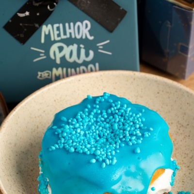 bolo pequeno coberto de glacê azul com confeitos e caixa azul com fita preta e texto MELHOR PAI DO MUNDO