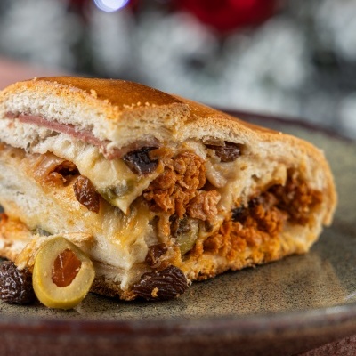 Fatias de pão recheadas com carne, queijo, azeitonas e passas num prato