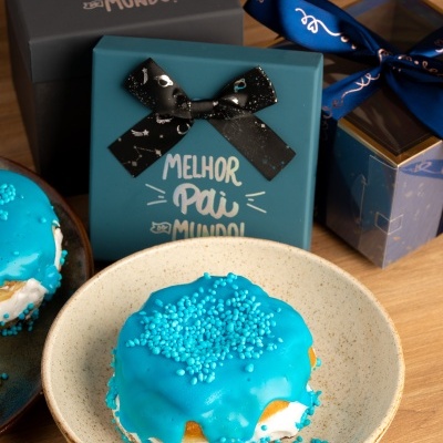 Dois bolos decorados com glacé azul e caixas de oferta com laços e texto MELHOR PAI DO MUNDO