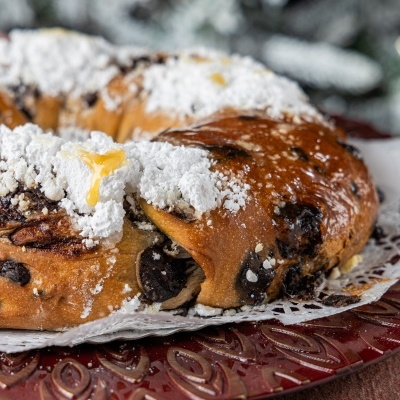 Bolo doce em forma de coroa com chocolate e açúcar em pó no prato vermelho decorativo.