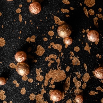 Bolas decorativas metálicas douradas e cobres sobre fundo preto com glitter dourado
