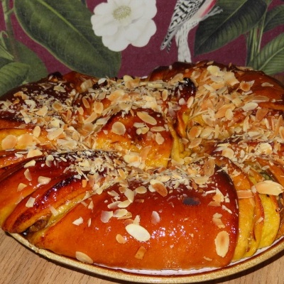 Pão doce coroado com amêndoas laminadas tostadas sobre base de madeira e tecido decorativo