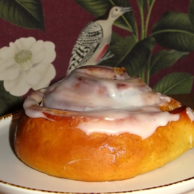 Rolo doce com glacê num prato branco com borda castanha