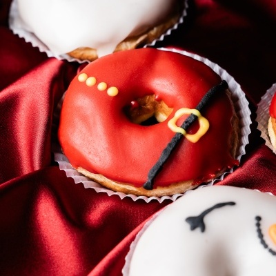 Donuts decorados em cores natalícias, vermelho e branco, sobre tecido vermelho