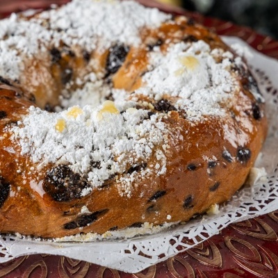 Bolo rei com frutas cristalizadas e açúcar em pó no prato vermelho decorado