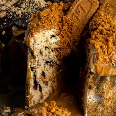 Panetone decorado com creme caramelizado e bolachas lotus no prato.