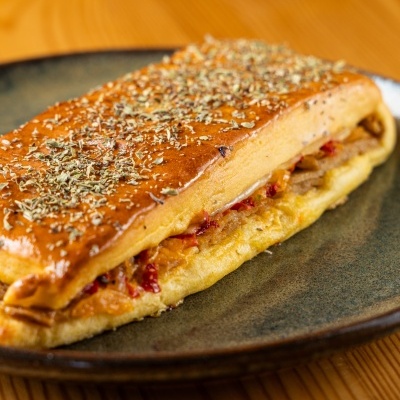 Sanduíche retangular com pão dourado polvilhado com ervas secas