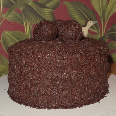 Bolo redondo coberto de granulado de chocolate com duas bolas de chocolate no topo