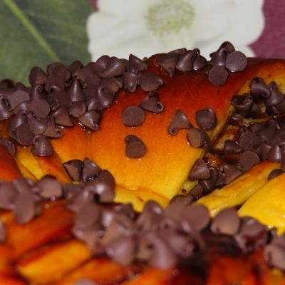 Croissant com gotas de chocolate num prato com padrão floral