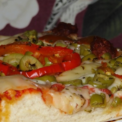 Pizza com queijo, azeitonas verdes, pimento vermelho e pedaços de carne, em base de massa branca fofa