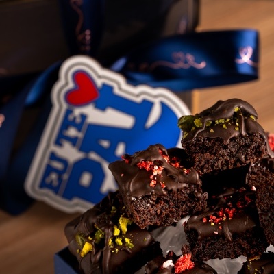 Bolos de chocolate com decoração vermelha e verde em caixa azul com fita e cartão