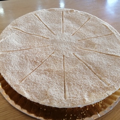 Tarte redonda polvilhada com açúcar em pó e cortes para fatias