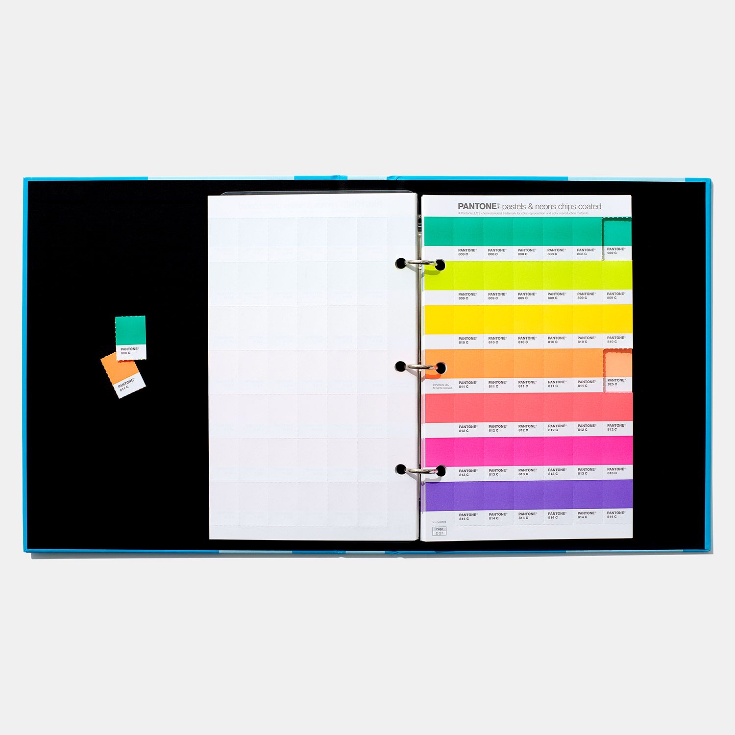 Livro Pantone aberto com páginas coloridas e duas cartas de cor ao lado