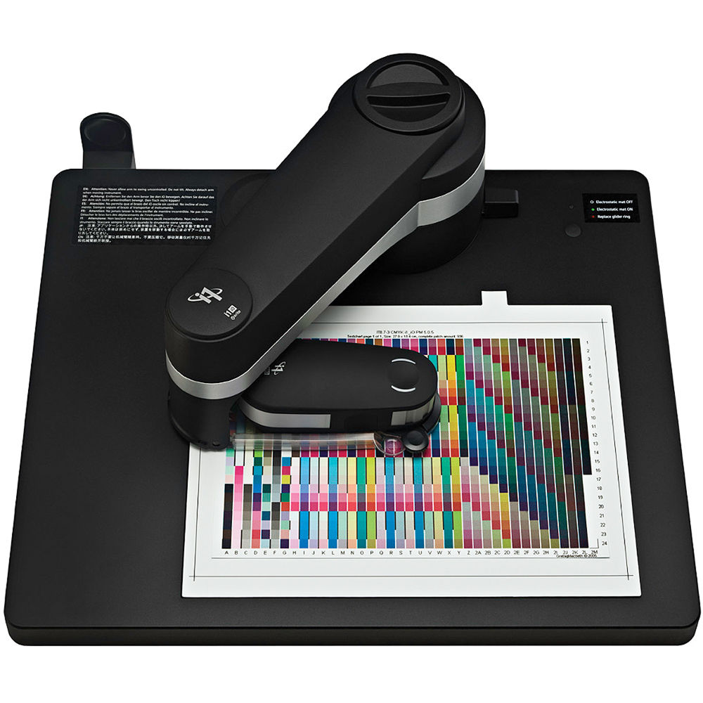 Máquina de medição de cores preta sobre base preta medindo papel com padrão multicolorido