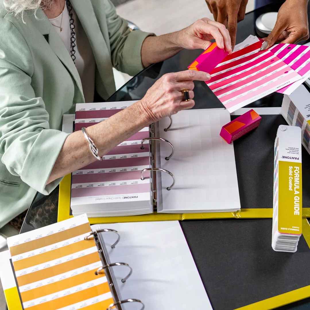 Folhas de amostras de cores Pantone em binders de anéis com pessoas a manusear