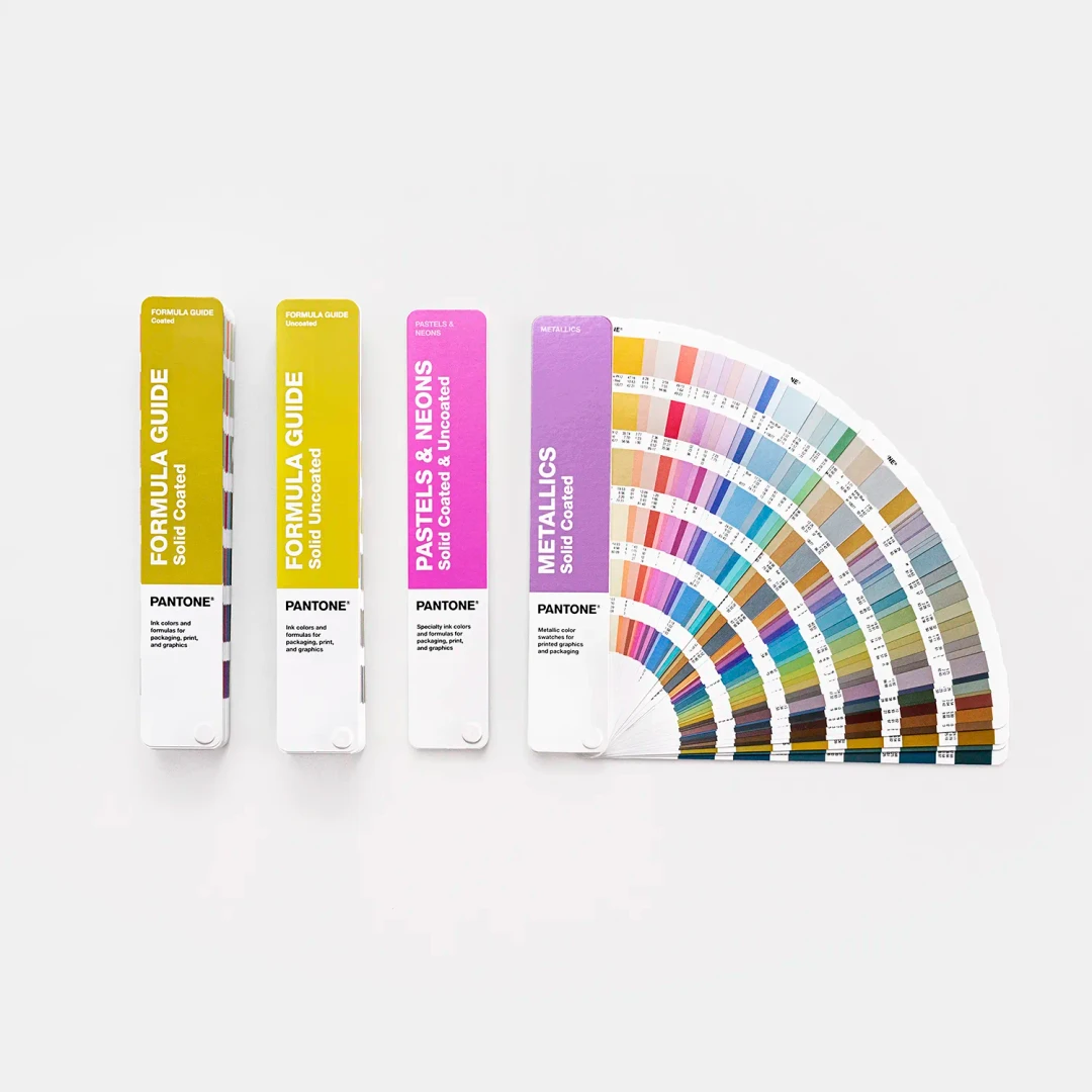 Guias de cor Pantone com capas coloridas e amostras de cores organizadas em leque.