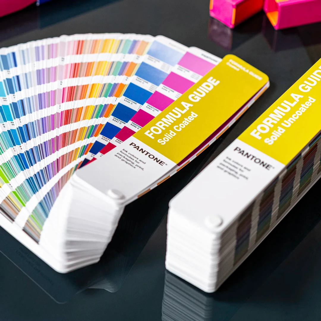 Catálogos de amostras de cores Pantone com capas amarelas sobre mesa escura