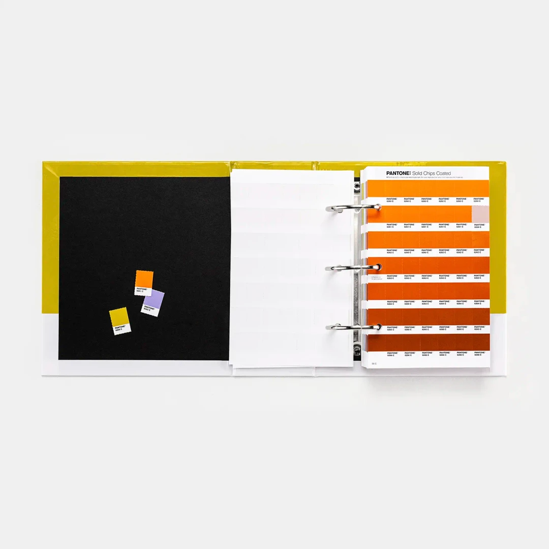 Catálogo Pantone aberto com amostras de cor em tons de laranja, amarelo e roxo