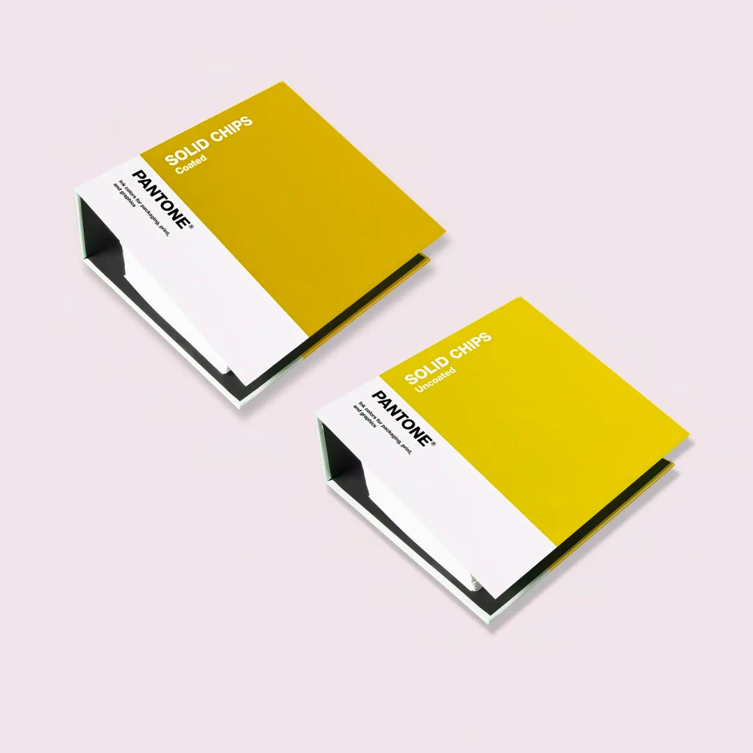 Livros de amostras de cor Pantone amarelo mostarda e branco sobre fundo rosa
