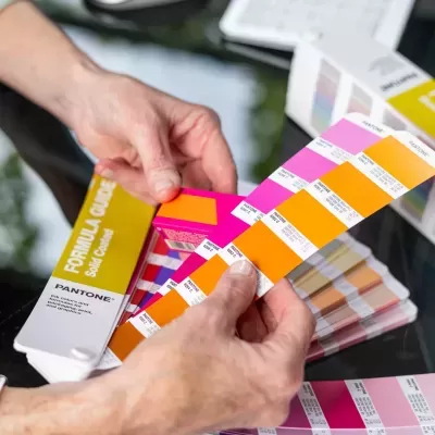 Folhas Pantone para seleção de cores em tons laranja e rosa, com texto FORMULA GUIDE Solid Coated.