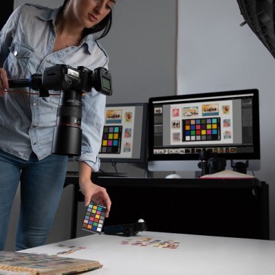 Mulher a fazer calibração de cor num estúdio fotográfico com cartão colorido e equipamentos de captura