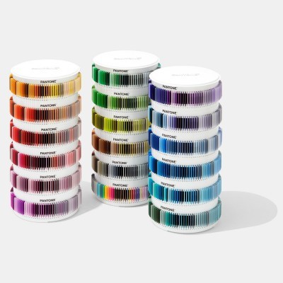 Rolos de fitas coloridas Pantone empilhados por cores em fundo branco.