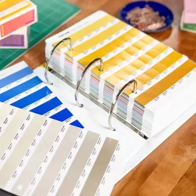 Livro de amostras de cores Pantone com várias tonalidades sobre mesa de madeira