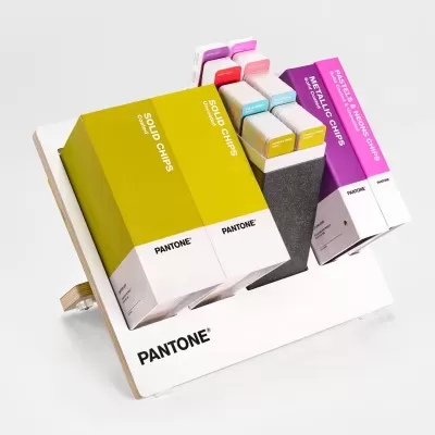 Conjunto de amostras de cores Pantone com caixas coloridas e suporte branco com base de madeira.
