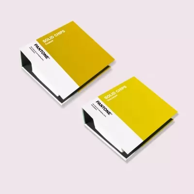 Livros de amostras de cor Pantone amarelo mostarda e branco sobre fundo rosa