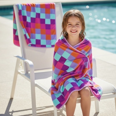 Toalha de praia colorida quadrados padrão com criança e cadeira junto à piscina