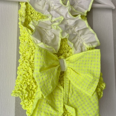 Fato de banho amarelo fluorescente com grande laço e detalhes brancos pendurado