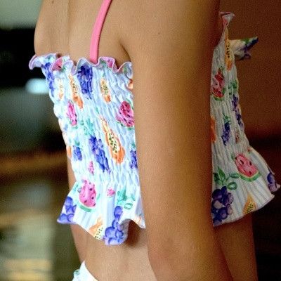 Top de criança com alças rosa e padrão de frutas coloridas com folho