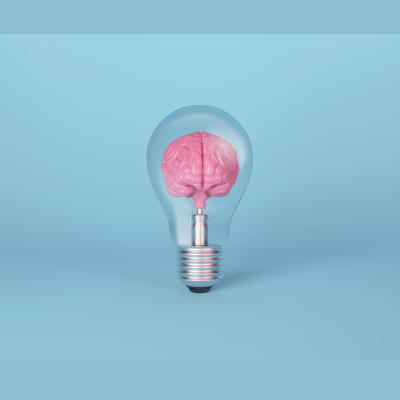 Lâmpada transparente com cérebro cor de rosa dentro em fundo azul claro