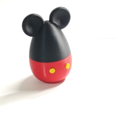 Objeto decorativo ovoide com topo preto, orelhas redondas, parte inferior vermelha e botões amarelos