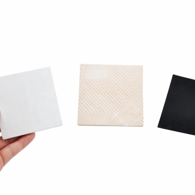 Três pastilhas quadradas nas cores branca, bege com padrões e preta, sobre fundo branco