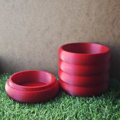 Seis tigelas vermelhas de plástico, cinco empilhadas e uma separada, sobre relva artificial