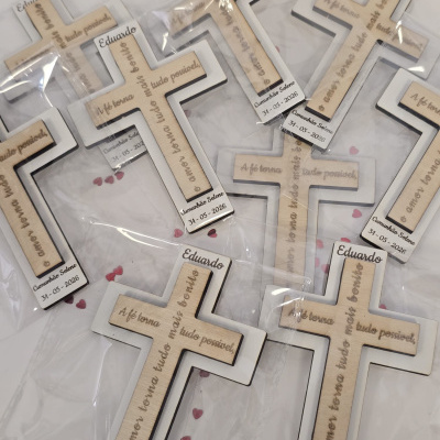 Cruz de madeira com moldura branca em embalagem transparente com texto e data