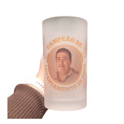 Copo de vidro fosco com imagem e texto em português segurado por mão com manga castanha