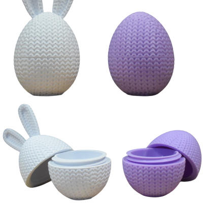 Recipientes em forma de ovo com textura trançada, branco com orelhas de coelho, lilás, abertos para mostrar o interior.