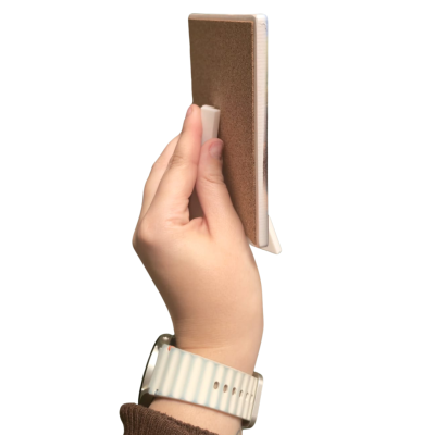 Mão segurando bloco com capa castanha e suporte branco