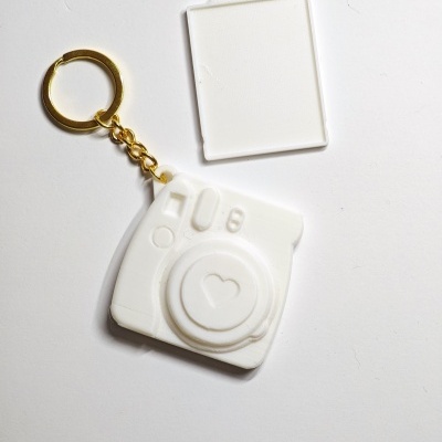 Chaveiro branco formato câmara fotográfica com argola dourada