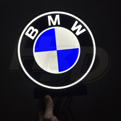 Logotipo iluminado da BMW redondo em fundo preto.