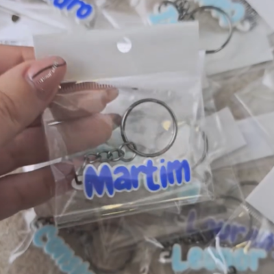 Porta-chaves personalizados com nomes em acrílico azuis embalados em sacos transparentes.