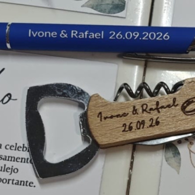 Caneta azul e porta-chaves de madeira com gravações para casamento sobre cartões com texto em português.