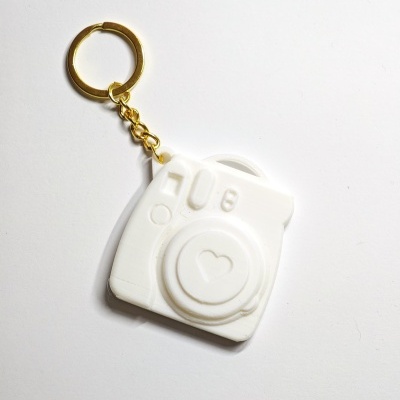 Chaveiro branco em forma de câmara fotográfica com argola dourada