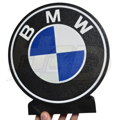 Emblema BMW azul, branco e preto segurado por uma mão