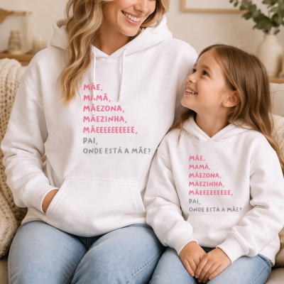Mulher e menina com hoodies brancos com texto em português sentadas num sofá bege.