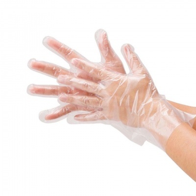 Par de luvas plásticas descartáveis transparentes em mãos sobre fundo branco