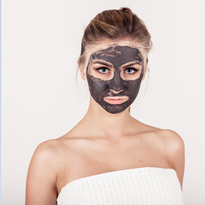 Mulher com máscara facial preta e toalha branca